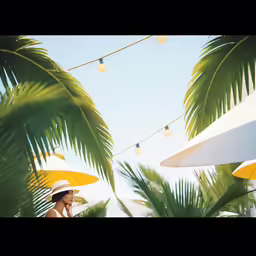 a woman wearing white hat talking on her phone under palm trees