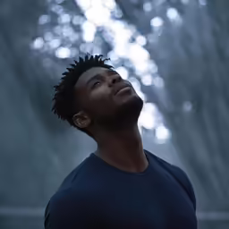 the young black man with his head turned, stares up