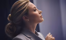 the woman in a business suit is holding her hands together