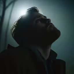 a man staring up at the sky with sun light behind