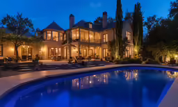 a large house with a lit pool at night