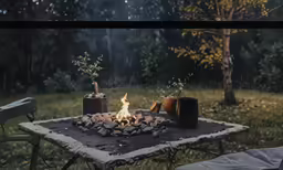 a table topped with a small fire pit in the middle of a field