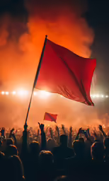 someone is holding up a red flag as fireworks and smoke are being thrown behind him
