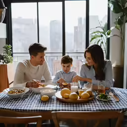a man and woman sitting at a table with children eating food