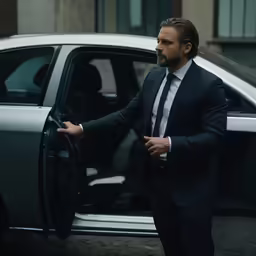 a man in a suit standing near a car