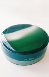 green object with light reflection on white surface