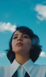 a woman in a black suit is staring upward