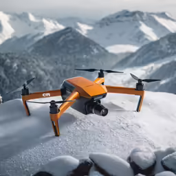 an orange remote controlled flying device sitting on top of snow covered rocks