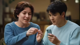 two people using cell phones on a table