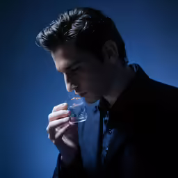 a young man drinks from a wine glass