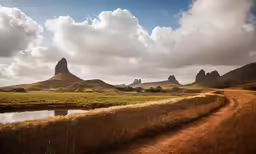 a dirt road winding through a grass covered field