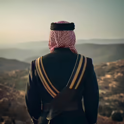 an arabic man in traditional clothes looking over a mountain