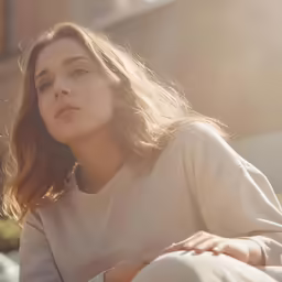 a woman with her eyes closed sits on the ground