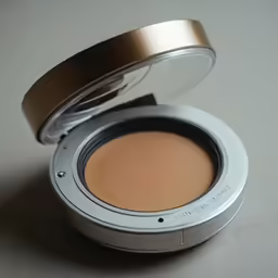 a round, metallic lid container filled with foundation on top of a counter