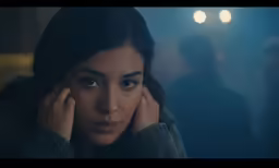 a woman looking at the camera with her hands to her face