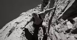 a man climbing up the side of a large rock