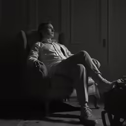 a man sitting in an old chair and smoking a cigarette