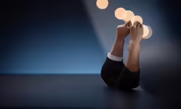 a woman sitting down with her legs crossed and lights above