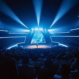 an audience in an arena at night looking out on stage