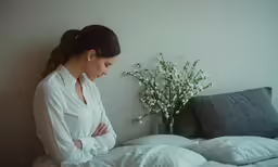 a woman standing in front of a vase on a bed