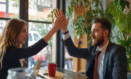 two young people with business suits and ties giving high five to each other