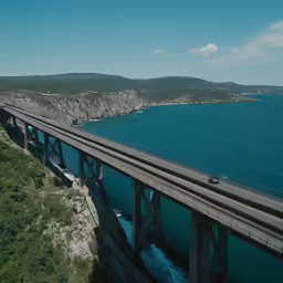 a car driving on a bridge over blue water