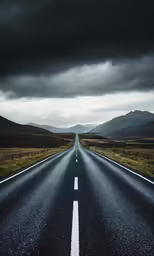 the road with white lines on it goes through some mountains