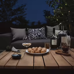 a wooden table topped with a plate of food and two wine glasses