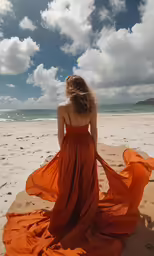 a woman in a long red dress walks on the beach