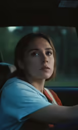 a young lady driving a car is looking at the camera