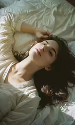 a woman laying in a bed next to white sheets