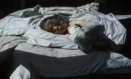 a young person is lying in a bed