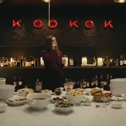 a woman is talking on her phone as she stands near an assortment of food