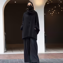 a woman wearing black stands outside a building
