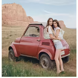 two girls pose next to an old truck