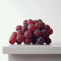 the grapes are sitting on a white surface