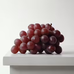 grapes resting on white stone plate in front of white background