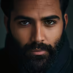 a man with long beard and wearing a black coat