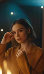 a woman wearing an orange shirt standing in front of a lit candle