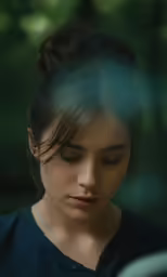 woman looking down at her cell phone with forest in background