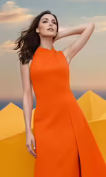 a woman wearing an orange dress stands on a beach