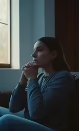 a woman sitting on top of a couch in front of a window