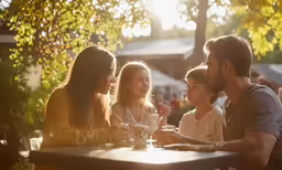 four adults sitting at a table talking with one child