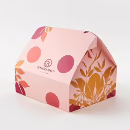 a pink, florally designed box is on a white table