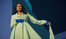 a woman in a light green dress holding on to her long gloves