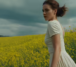 a woman in a white dress stands in a field