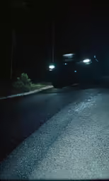 a car driving down the street with headlights on