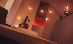 the lamp is above a shelf with bottles on it