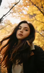 woman with long hair standing in an autumn forest