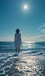 a woman in a dress walks along the shoreline in front of the sun